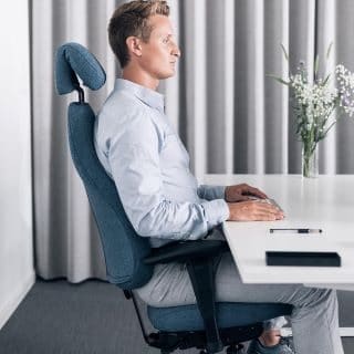En ansat sidder på Malmstolen kontorstol med armlæn og nakkestøtte